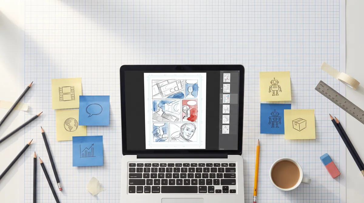 Top-down photo of a drafting table with a laptop showing a pencil-drawn comic editor, surrounded by sticky notes with sketches.